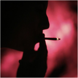 Silhouette of a man smoking a cigarette against a red glow